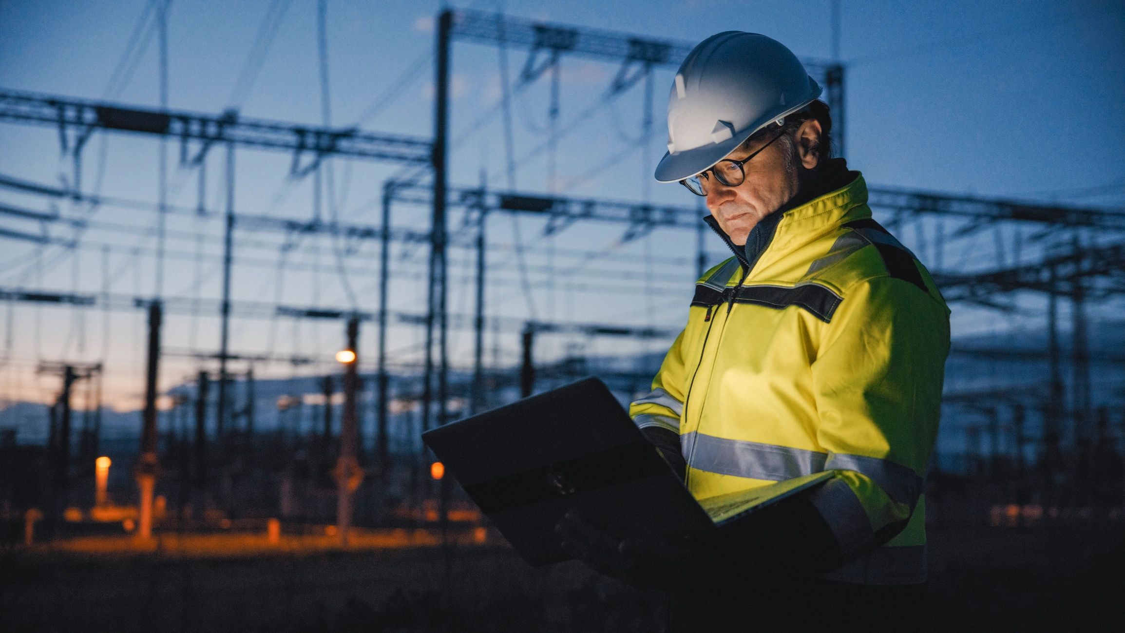Middle-aged foreman reviewing operations at an industrial site at twilight